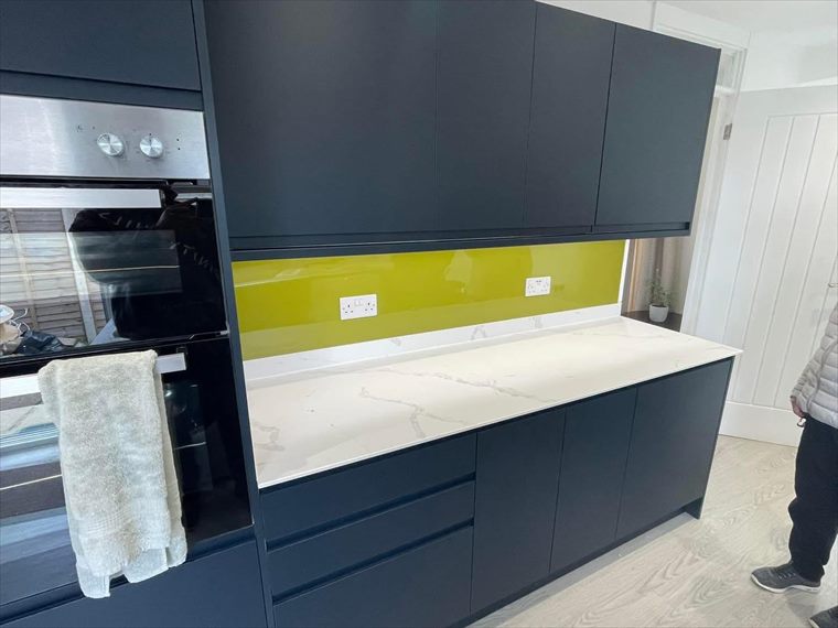 Navy units with a green glass splashback